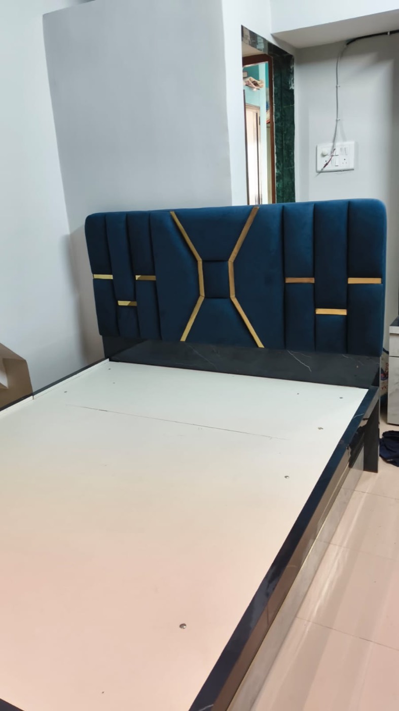 Bed with blue velvet cushioned headboard and gold strip detailing.
