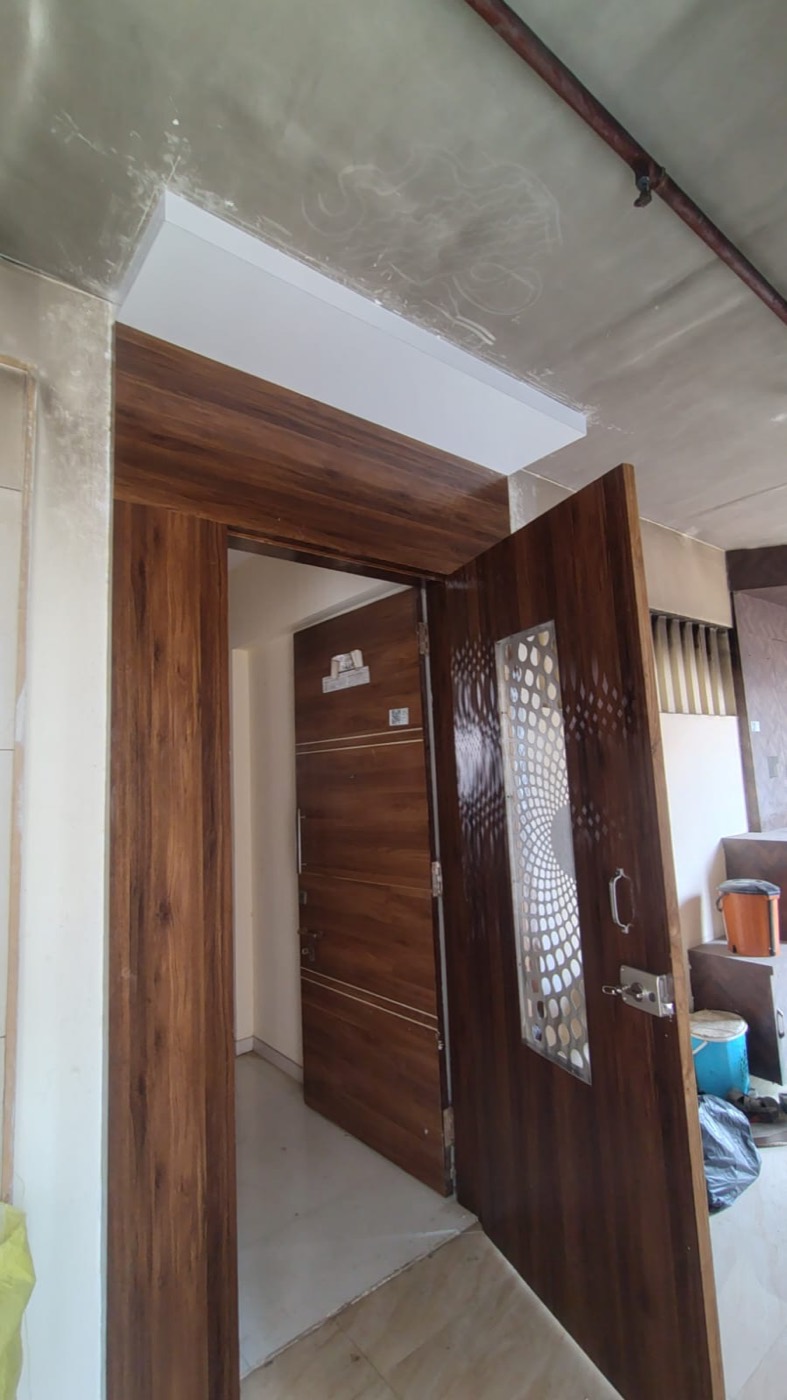 Door frame clad in wood-finish laminate with a white false ceiling band above.