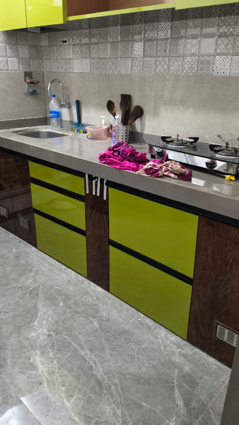 Modular kitchen with olive green high-gloss shutters and grey quartz counter.